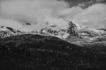 Snow on mountain tops with low clouds and shaded forest