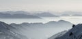 Snow Mountains Panorama in low lying inversion valley fog. Silhouettes of foggy Mountains. Scenic snowy winter landscape Royalty Free Stock Photo