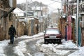 Snow in an old and unmodernised part of Baku, with coloured houses, a lone figure, and a car