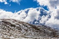 Snow patches on mountains and fluffy clouds on bright sunny day Royalty Free Stock Photo