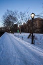 Snow pathway at park with light pole and trees