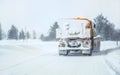 Snow plow gritter maintenance truck on winter road, completely white after heavy blizzard, view from rear Royalty Free Stock Photo