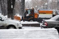 Snow plow is sprincling salt or de-icing chemicals on pavement in city. Cleaning service. Frost winter season.
