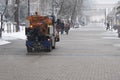 Snow plow is sprincling salt or de-icing chemicals on pavement in city. Cleaning service. Royalty Free Stock Photo