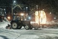 snow plow tractor clears a snowy road in public park after severe blizzard. Night winter scene Royalty Free Stock Photo