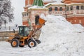 Snow removal by city utility vehicles. The CASE wheel front-loader is raking a huge snowdrift with a bucket next to