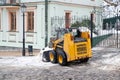 Snow removal grader. A municipal service tractor cleans snow from the street. Kiev. Ukraine. 02/23/2021