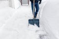 Snow removal, a man cleans the snow with a blue shovel near his house. Royalty Free Stock Photo