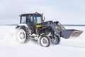 Snow removal vehicle on the road. Snow plow tractor is cleaning a city embankment after snowstorm