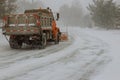 The snow-removing car cleans the road on heavy snowfall