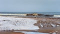 Snow, sand and big waves of a winter sea