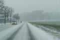 Snow storm on a country road and dangerous road conditions in winter with cars driving Royalty Free Stock Photo