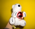 Snow-white teddy bear with red Christmas tree toy in hands on yellow background Royalty Free Stock Photo