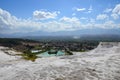 Snow-white travertines against the background of mountains, city and summer blue sky with clouds in Pamukkale, Turkey Royalty Free Stock Photo