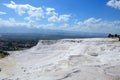 Snow-white travertines against the background of mountains and summer blue sky with clouds in Pamukkale, Turkey Royalty Free Stock Photo