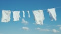 White linen dries on a rope against a clean blue sky Royalty Free Stock Photo