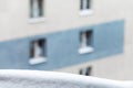 Snow on windowsill and city house on background