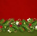 Snowberries with green twigs of Christmas tree, decorations and cones in a festive line arrangement on green and red craft paper