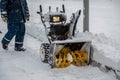 Snowblower parked in the park during a snowfall. Person goes to a snowplow.