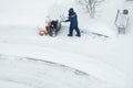 Snowblower removes snow, a man cleans the yard outside Royalty Free Stock Photo
