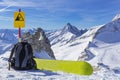 Snowboard equipment, a backpack and a snowboard lie on the edge of a cliff against the background of a panorama of mountains Royalty Free Stock Photo