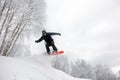 Snowboard jump under the white snowy forest in a good winter day, freeride in a deep snow, ski season