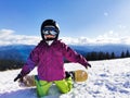 Snowboard Winter Sport. Little kid girl playing with snow wearing warm winter clothes. Winter background