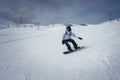 Snowboarder in action on snowy slope in overcast weather at developed ski resort. Royalty Free Stock Photo