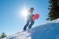 Snowboarder Climbing up with Red Snowboard in the Mountains at Sunny Day. Snowboarding and Winter Sports Royalty Free Stock Photo