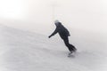 Snowboarder descends from a high mountain on a slope at winter cold day