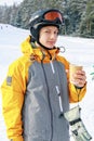 The snowboarder drinks hot coffee. A young guy of Caucasian ethnicity is holding a paper cup with a hot drink Royalty Free Stock Photo