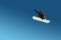 Snowboarder girl does a trick in jumping with a grab against the blue sky. Blue gradient background isolated athlete in Royalty Free Stock Photo