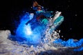 Snowboarder girl dressed in a orange and blue sportswear performs tricks on the snow