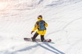 Snowboarder in a helmet and with a backpack on his back rides along a mountain track on a sunny day