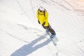 Snowboarder in a helmet and with a backpack on his back rides along a mountain track on a sunny day