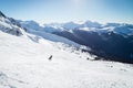 Snowboarder on a hill at the top of Blackcomb, 7th Heaven, with a view looking toward Whistler on a sunny day.