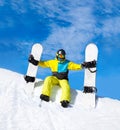 Snowboarder hold two snowboards sitting on snow