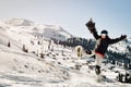 Snowboarder holding his snowboard over head kick snow happy feeling great in ski resort excited on holiday vacation solo. Sunny