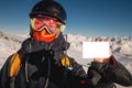 snowboarder holds an empty lift pass with a mountain in the background. Blank ski pass in the hand of a young skier in