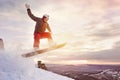 Snowboarder jumps against sunset sky