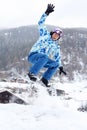 Snowboarder jumps on snowboard and waves by hand
