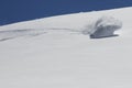 Snowboarder turning on fresh powder snow creating a snow wave