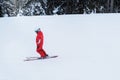 Snowboarder in red ski suit rises on lift up mountain slope. Ski sports in winter.