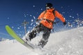 Snowboarder riding down the powder mountain hill on sunny day. S Royalty Free Stock Photo