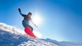 Snowboarder Riding Red Snowboard on the Slope in the Mountains in Bright Sun. Snowboarding and Winter Sports Royalty Free Stock Photo