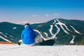 Snowboarder sitting on snow against mountains