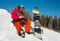 Snowboarder sitting in the snow at ski resort,using his smart phone while resting in the mountains Royalty Free Stock Photo