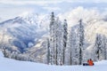 A snowboarder sitting on the snowy winter mountain slope of Sochi ski resort. Beautiful scenic landscape