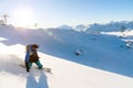 A snowboarder in a ski mask and a backpack is riding on a snow-covered slope leaving behind a snow powder against the Royalty Free Stock Photo