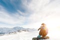 A snowboarder in a ski mask and a backpack is riding on a snow-covered slope leaving behind a snow powder against the Royalty Free Stock Photo